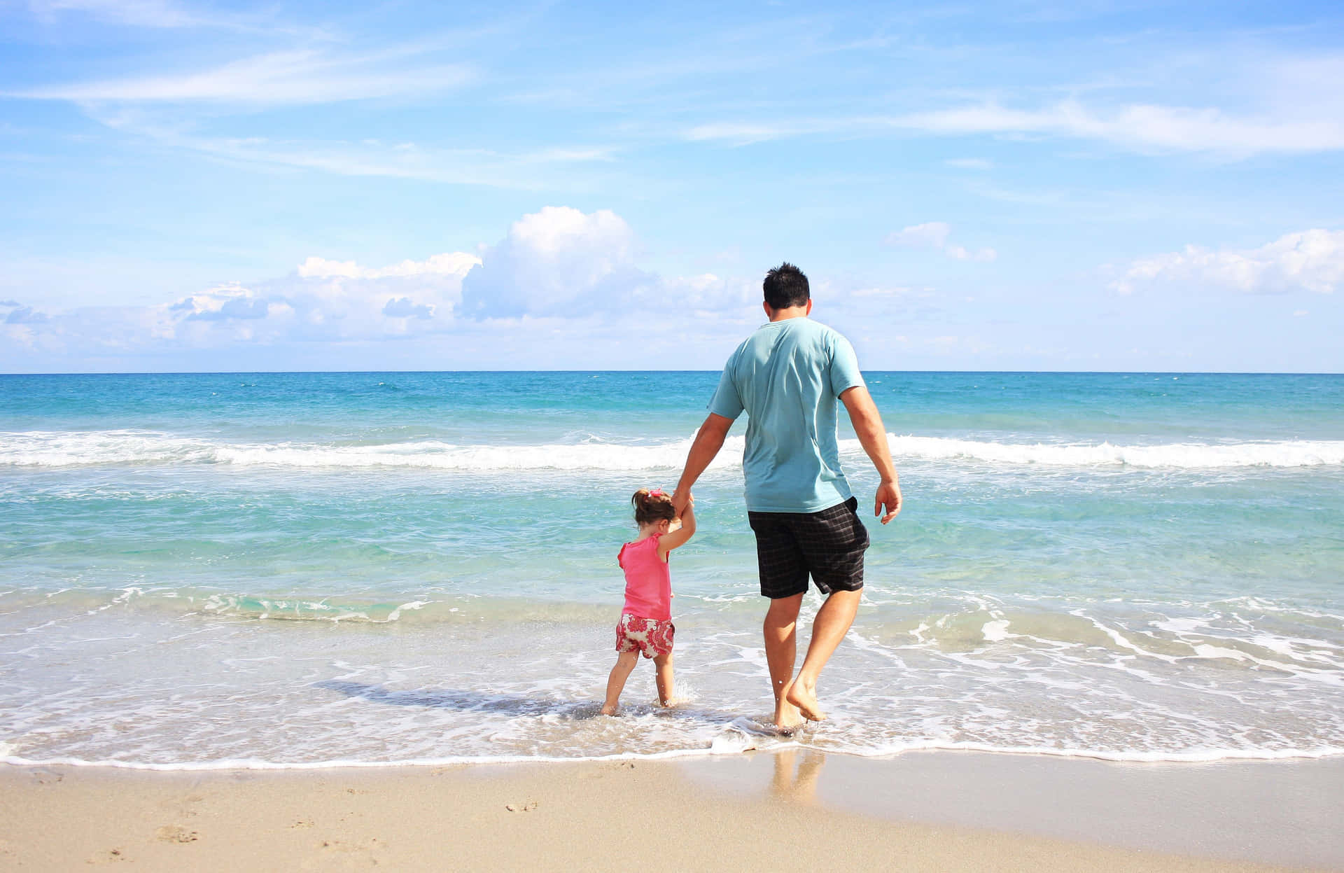 Fader og datter på strand med blå himmelbillede