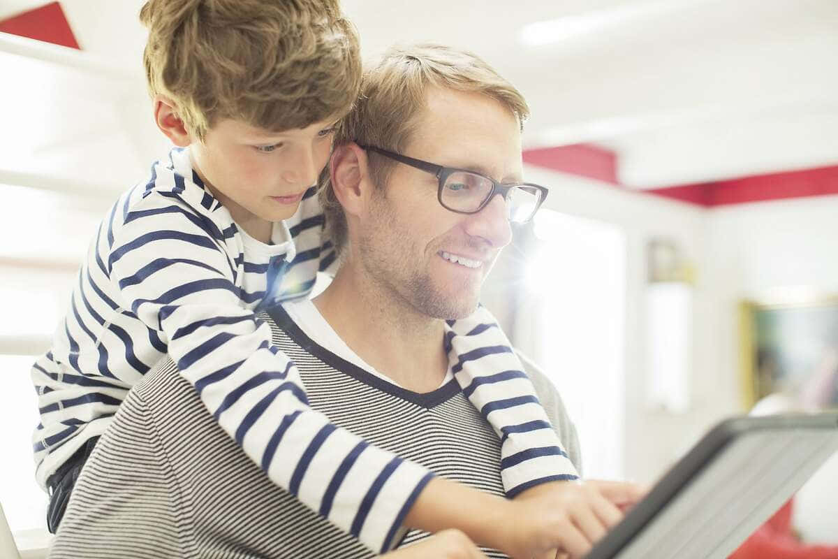A Man And His Son Are Using A Tablet Computer