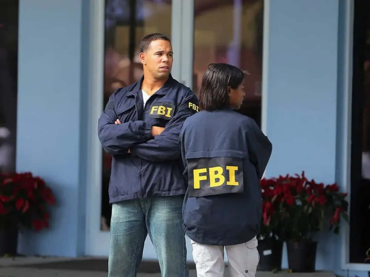 Two People Standing Outside Of A Building With Fbi Logos