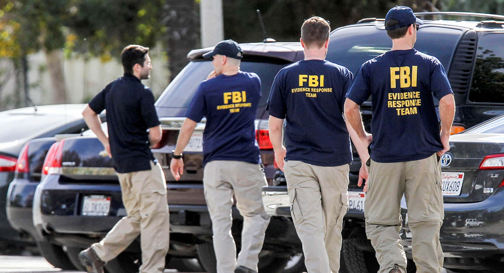 Fbi Agents Walk Past A Car In Front Of A Building