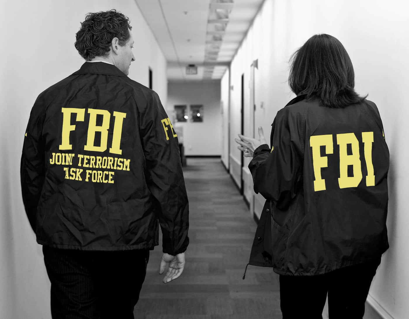Two People In Fbi Jackets Walking Down A Hallway Wallpaper