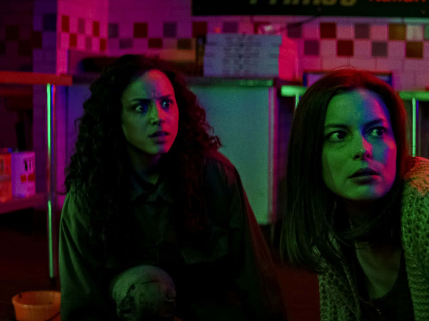 To kvinder i et mørkt rum med neonlys Wallpaper
