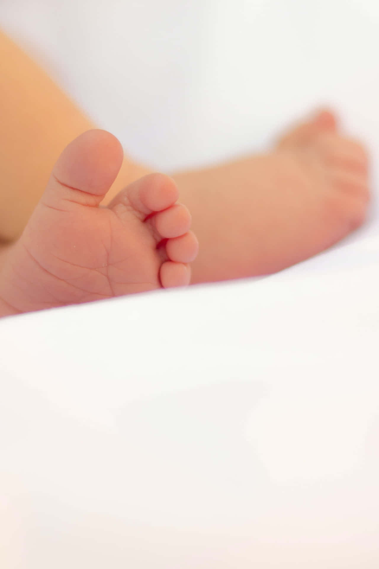A Close Up Of A Baby's Feet Laying On A Bed