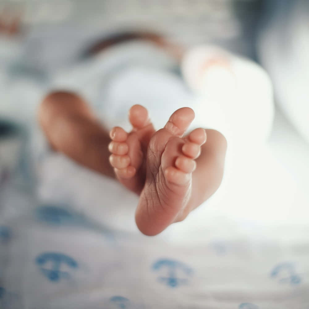 Lospies De Un Bebé Descansando En Una Cama.