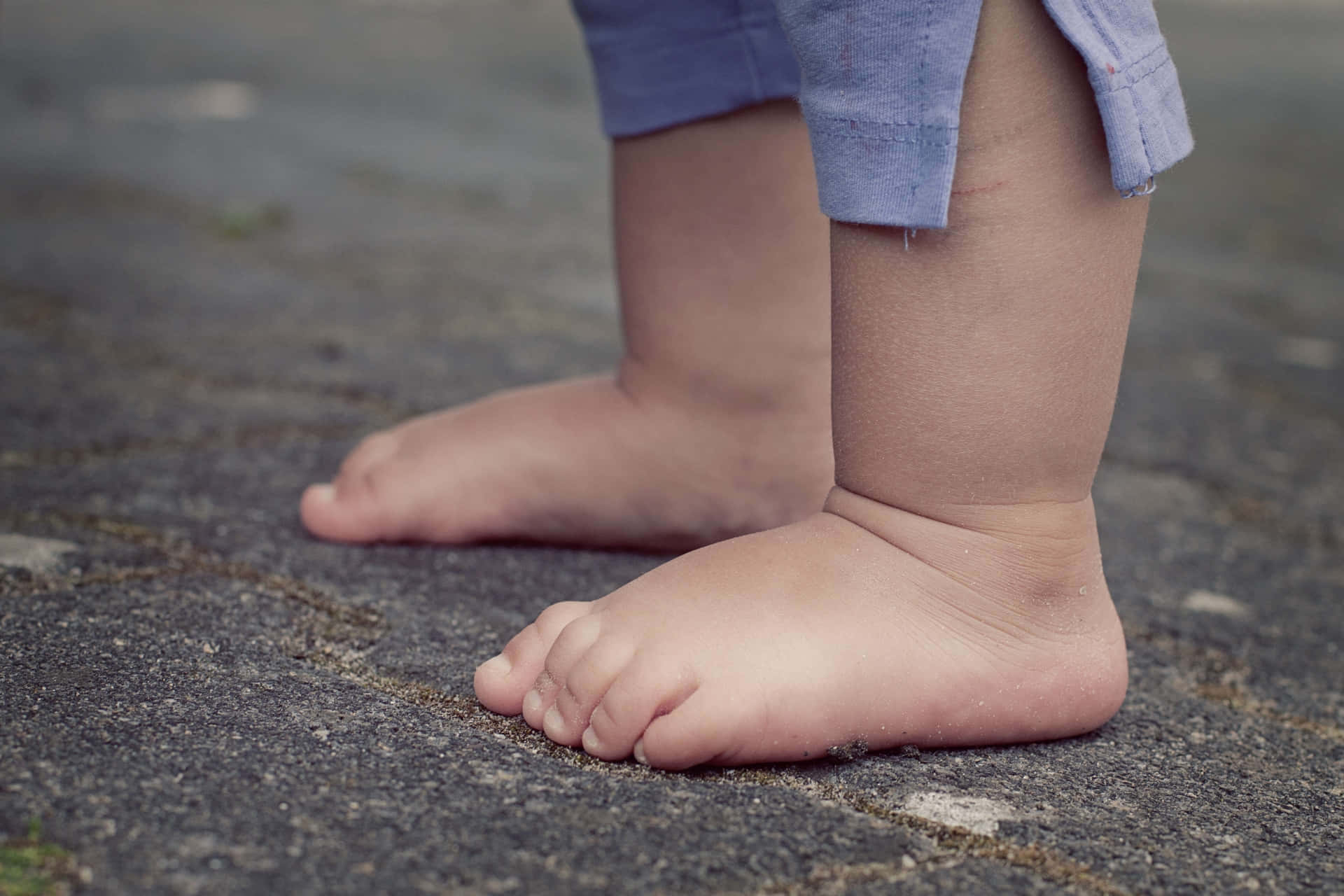 A Child's Feet Standing On A Sidewalk