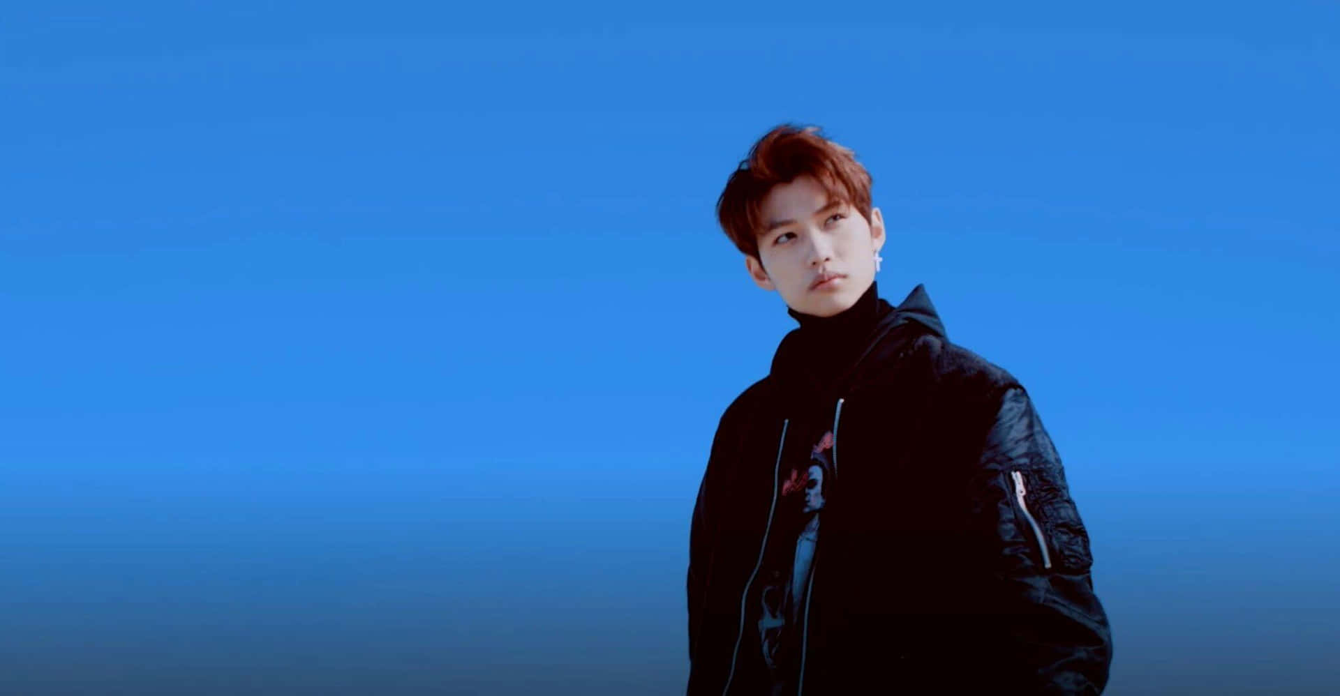 A Man In A Black Jacket Standing In Front Of A Blue Sky Wallpaper