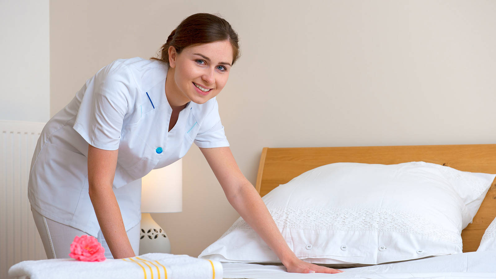 Female Housekeeper Smile Cleaning Bed Wallpaper