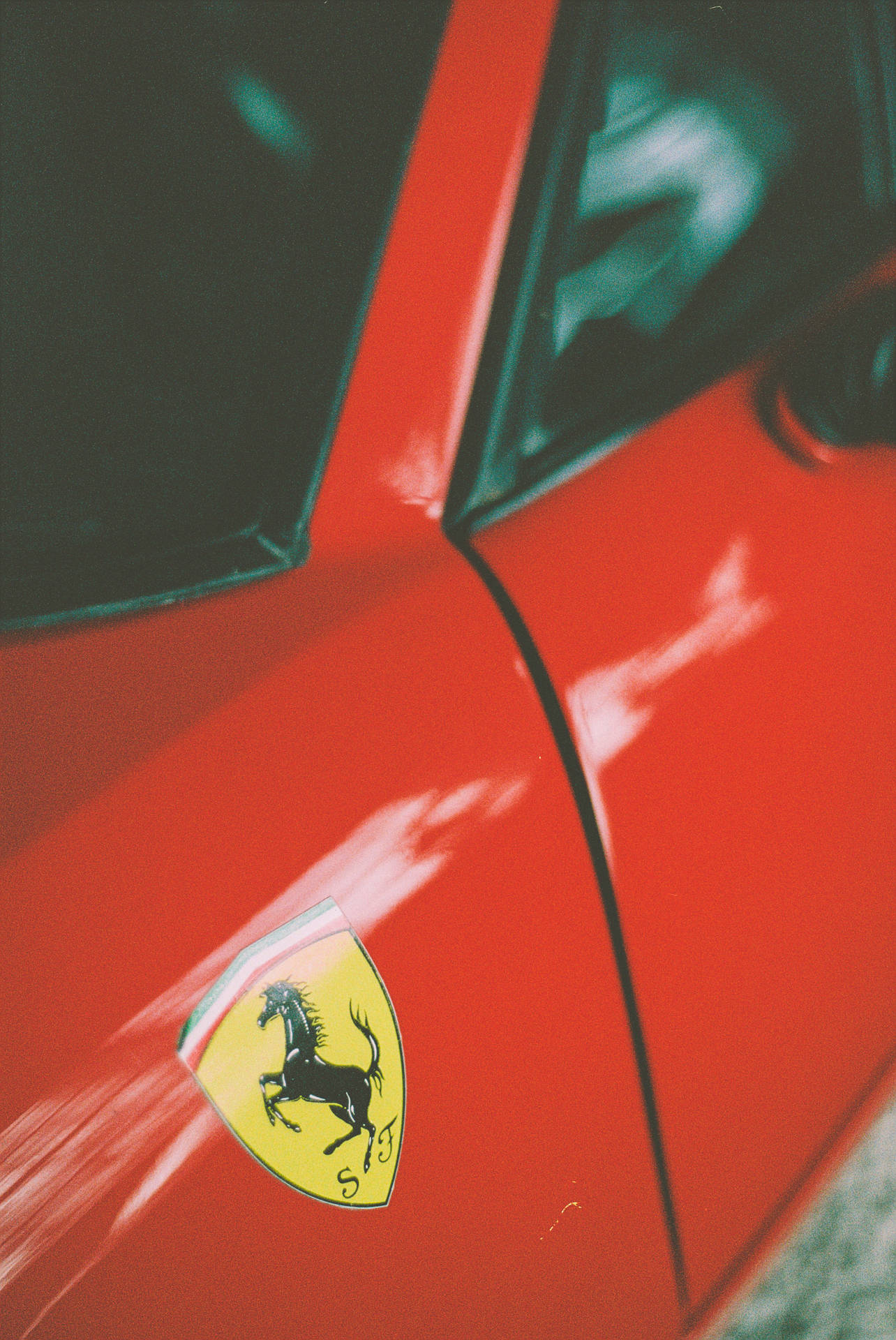 Ferrari sticker logo on red sports car mobile wallpaper.