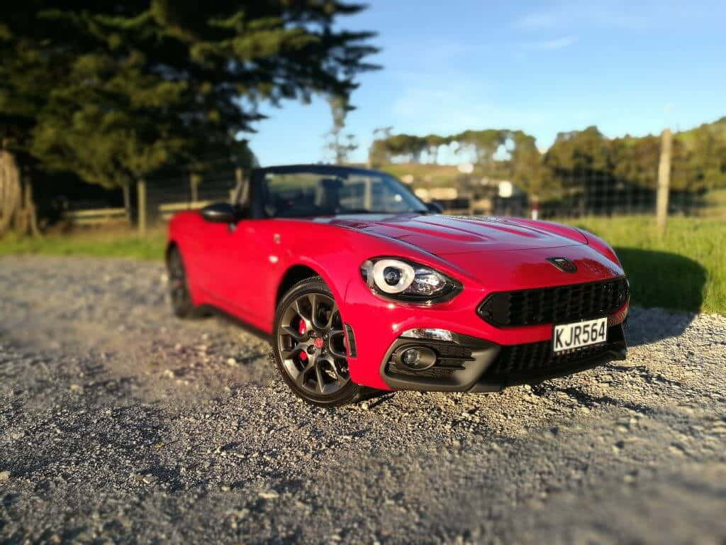 Caption: Sleek and Stylish Fiat 124 Spider on the Road Wallpaper