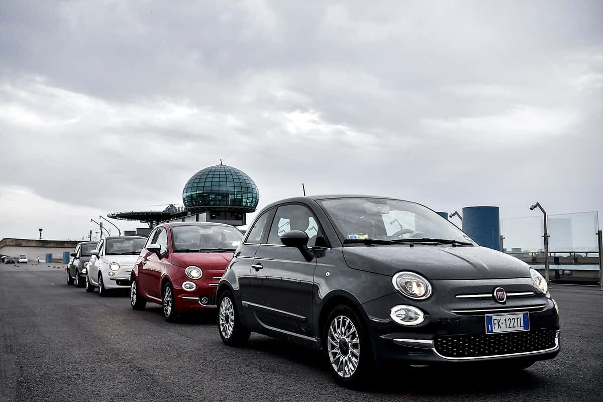 Sleek Red Fiat 500 Parked in Picturesque Venue Wallpaper