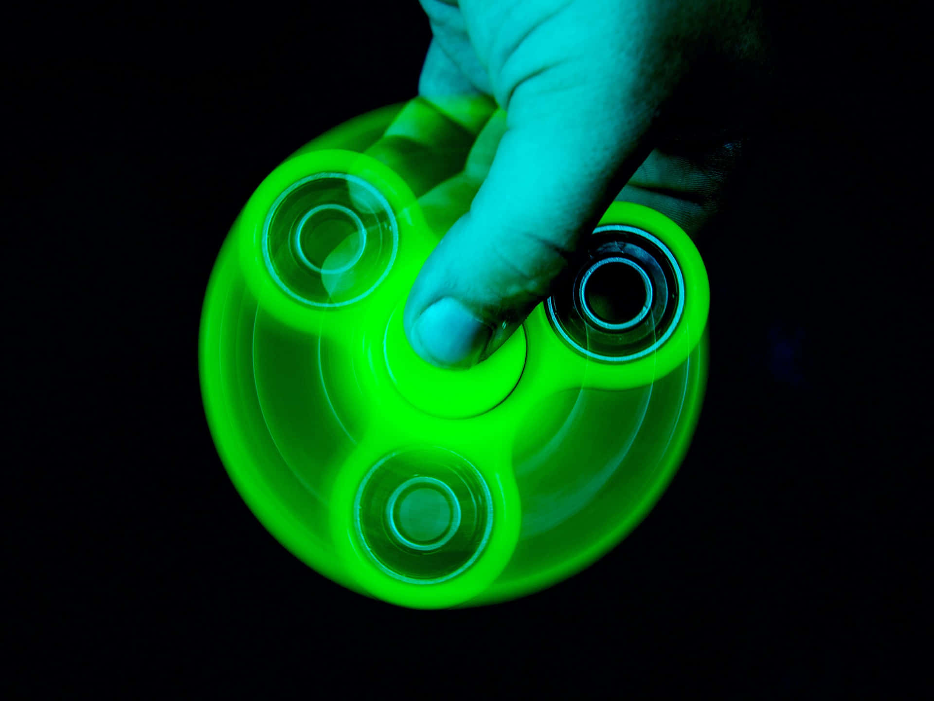 Unapersona Che Tiene In Mano Un Fidget Spinner Verde Che Emette Una Luce Verde.