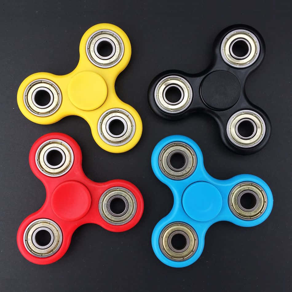 Four Different Colored Fidgetrs On A Black Surface