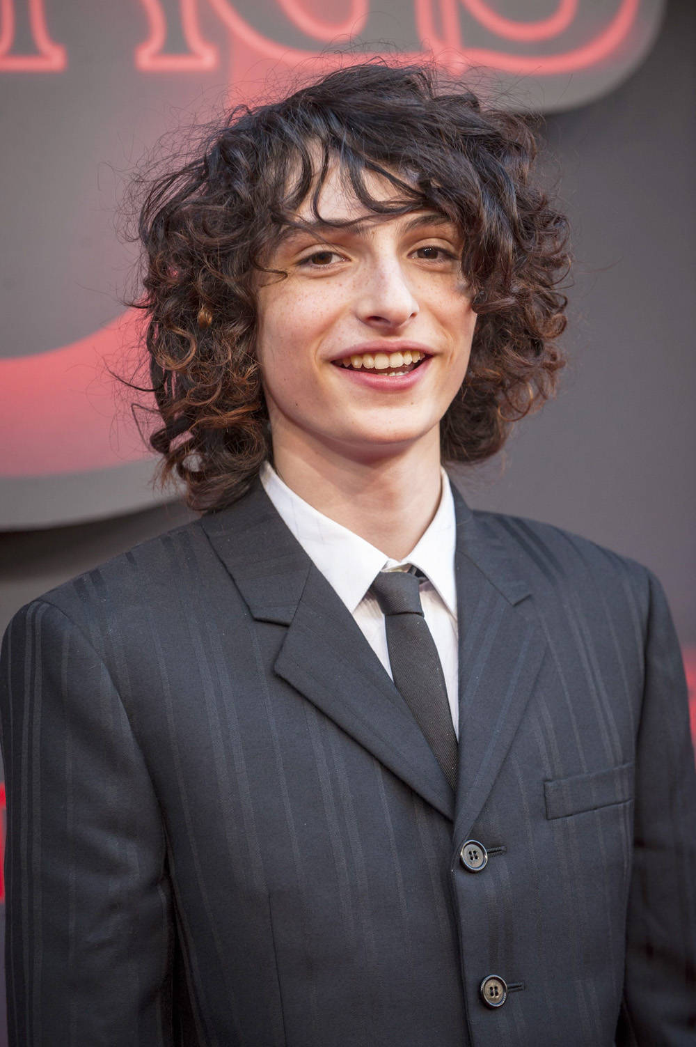 Finn Wolfhard Smiling On Stage Wallpaper