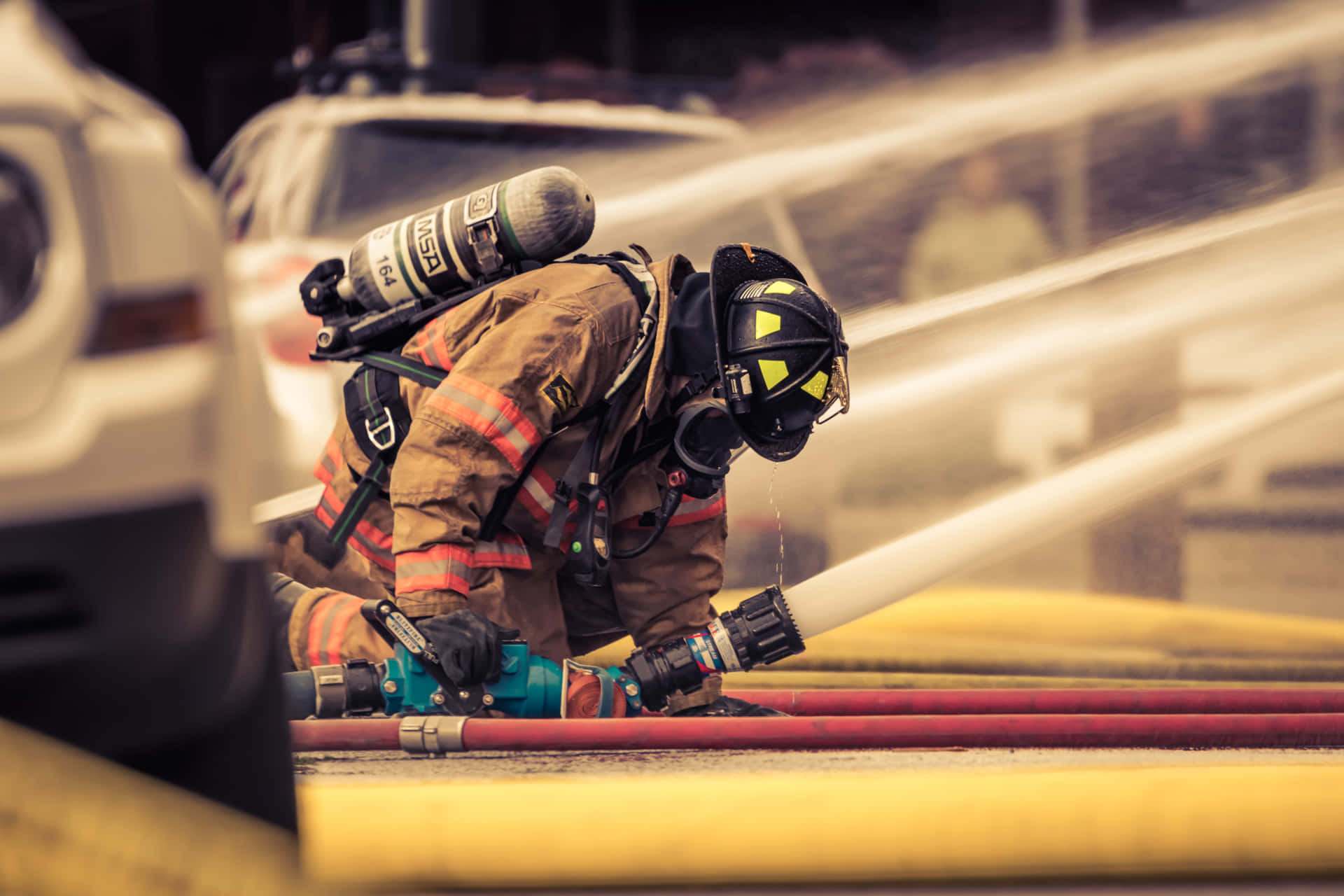 En brandmand sprayer vand på et brændende bygning Wallpaper