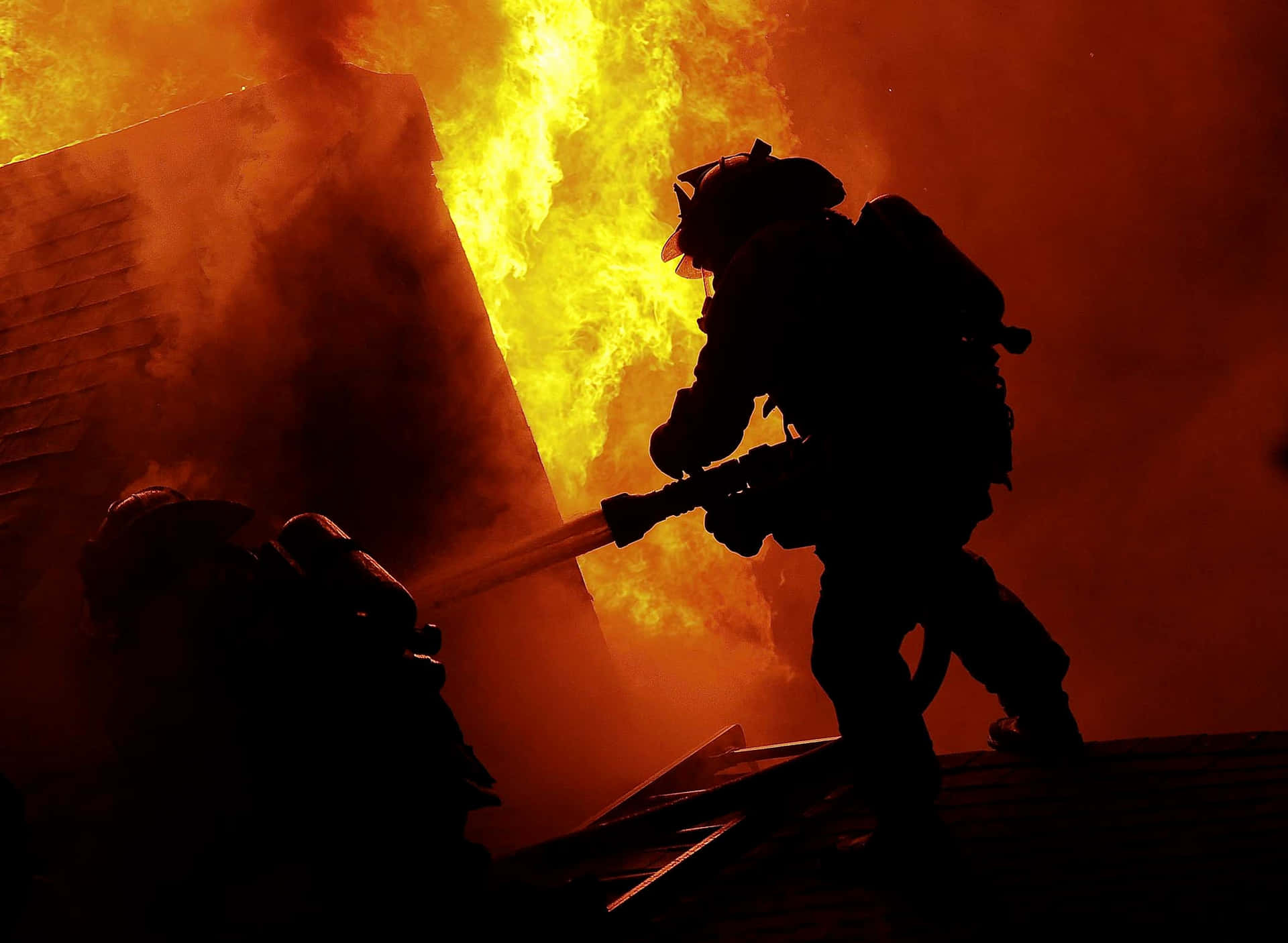 En brandmand kæmper mod en brand i et hus Wallpaper