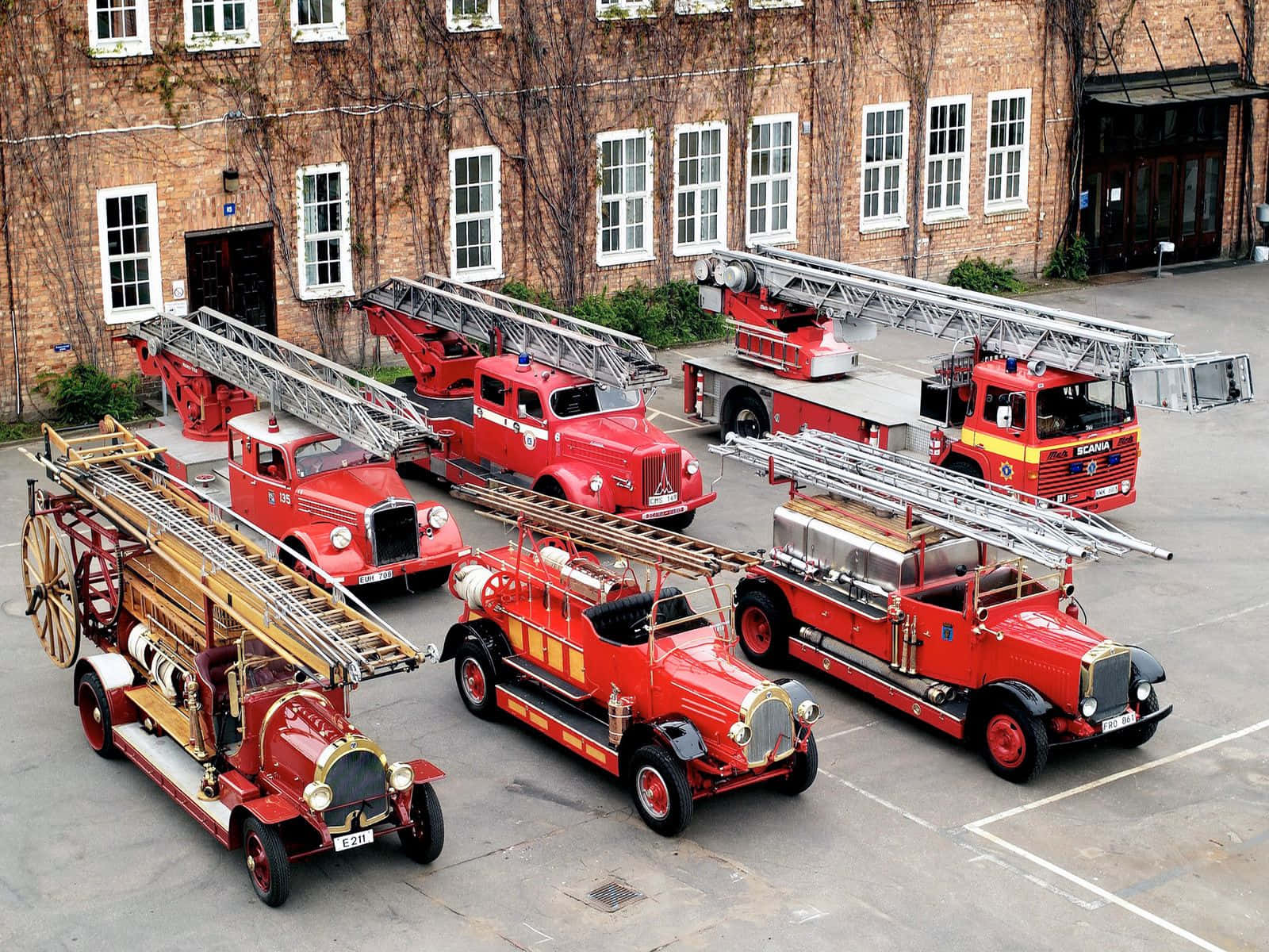 A Group Of Old Fire Trucks Parked In Front Of A Brick Building