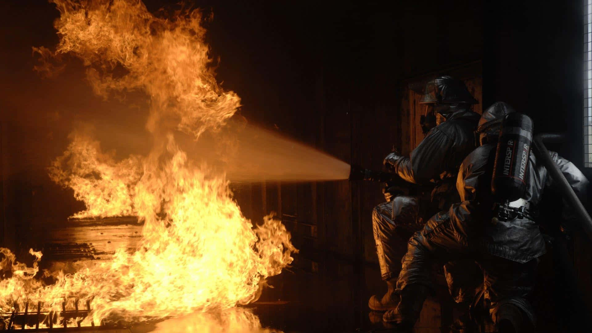 Zweifeuerwehrleute Kämpfen Gegen Ein Feuer In Einem Dunklen Raum.