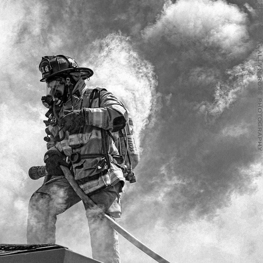 A Firefighter Is Standing On Top Of A Roof