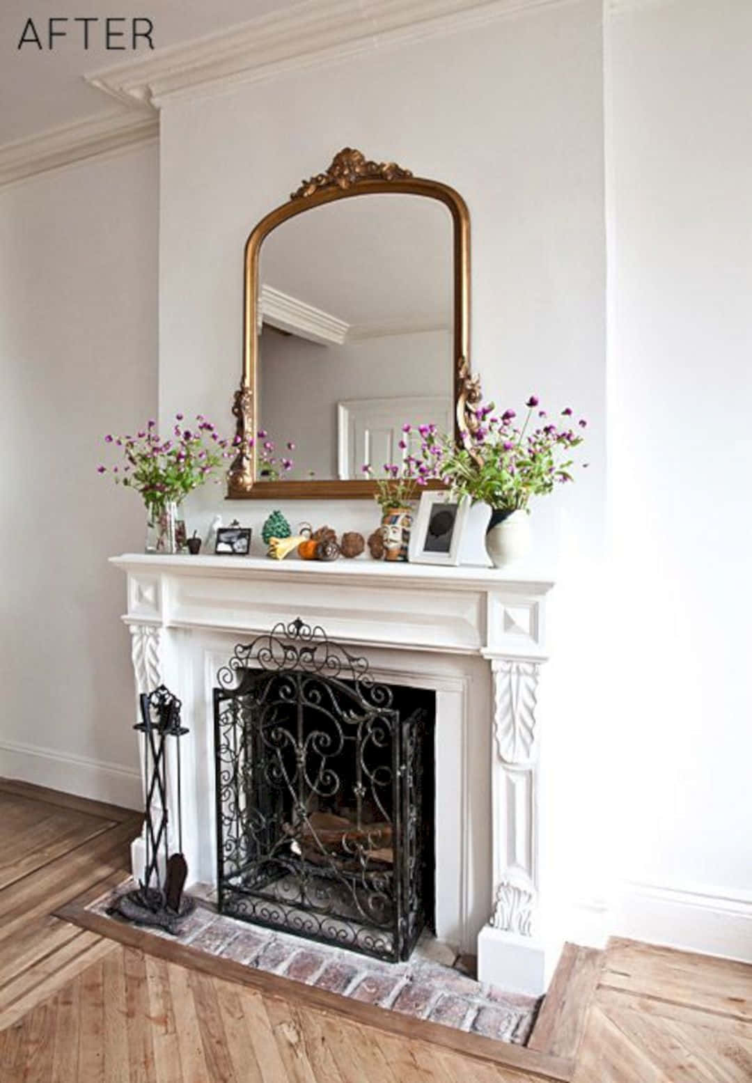 A Fireplace With A Mirror And Flowers In It