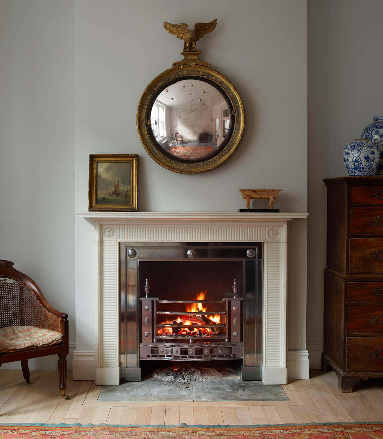 A Fireplace In A Room With A Chair And A Mirror
