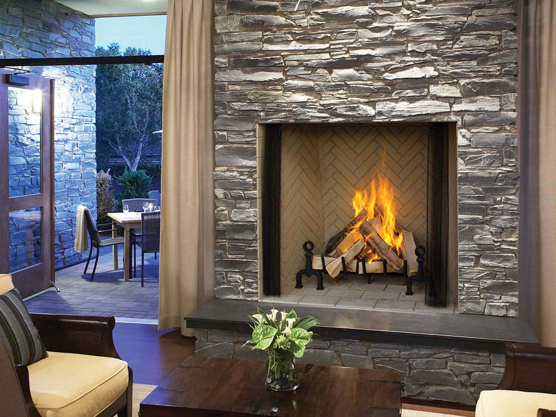 A Living Room With A Stone Fireplace And Patio
