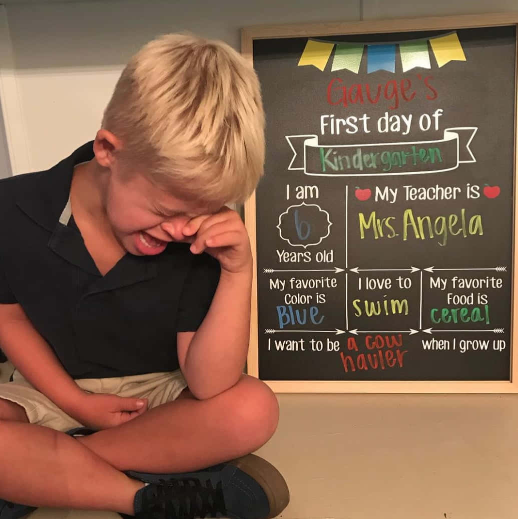 A Boy Is Sitting On The Floor With A Chalkboard