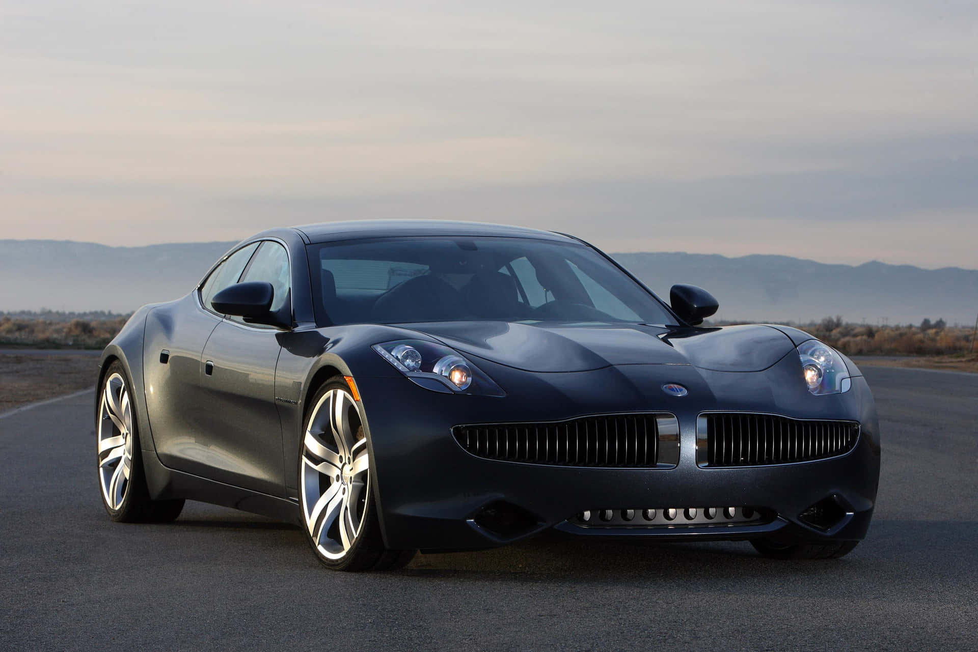 The Fisker Karma, a luxury electric vehicle on a scenic coastal drive. Wallpaper