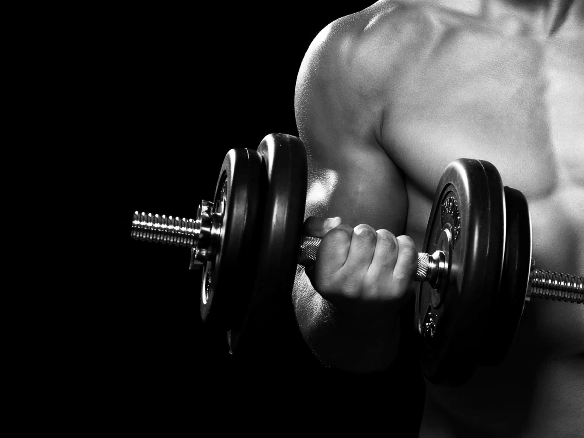 A Man Is Holding A Pair Of Dumbbells