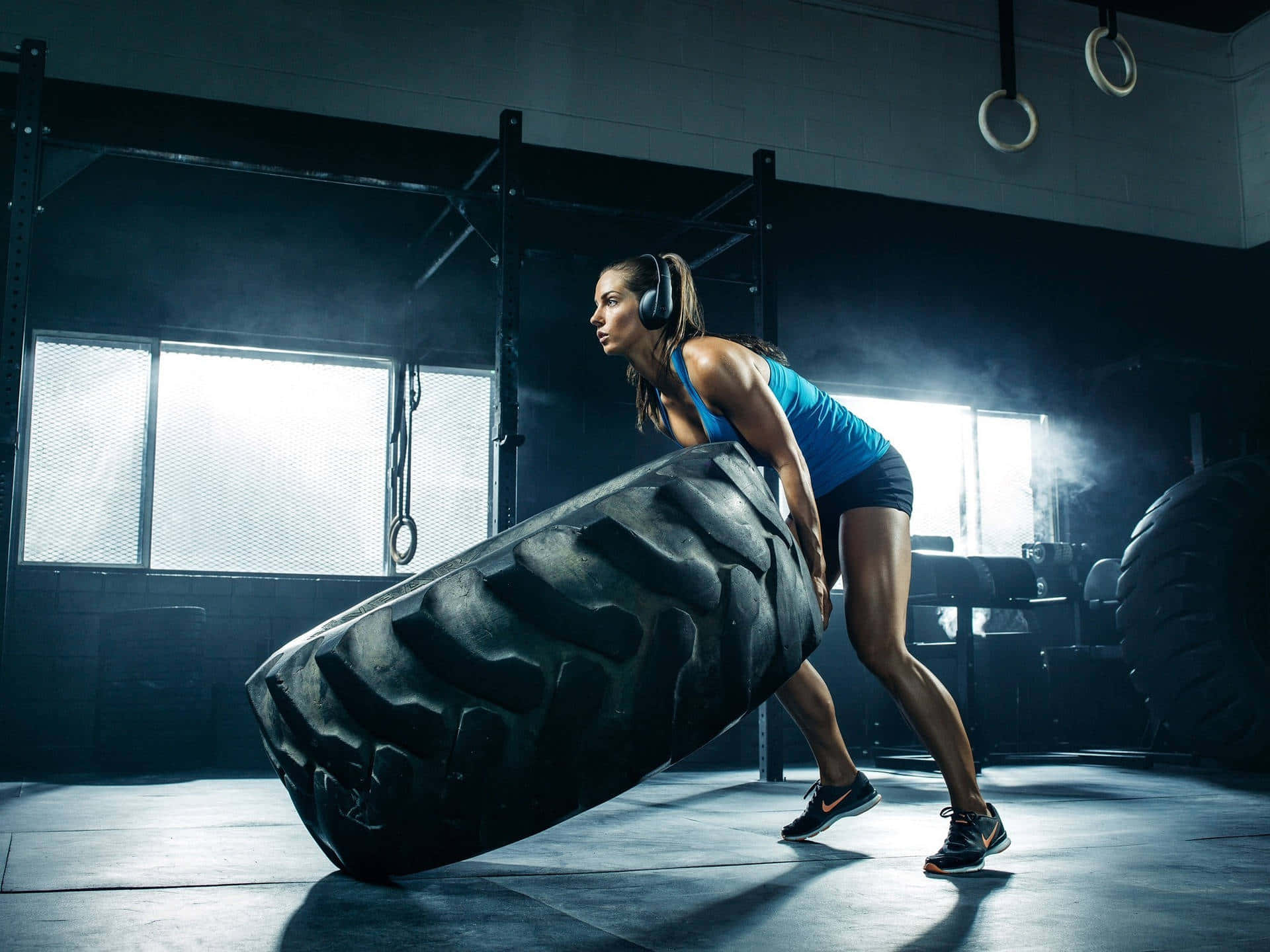 A Woman Is Lifting A Tire In A Gym