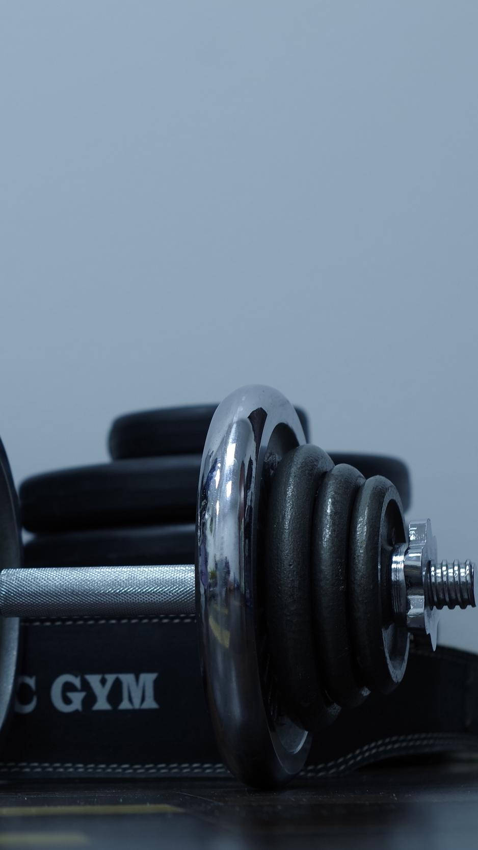 A Gym Dumbbell And A Black Belt On A Table Wallpaper