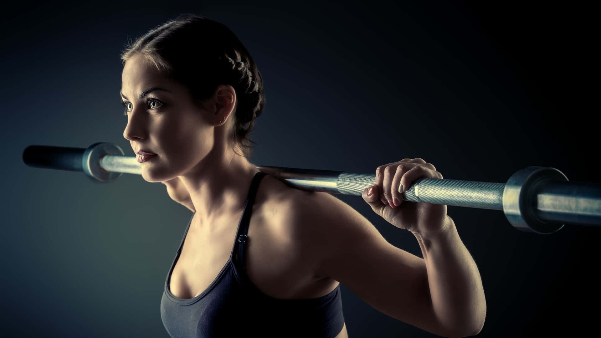 A Woman Is Lifting A Barbell On A Dark Background