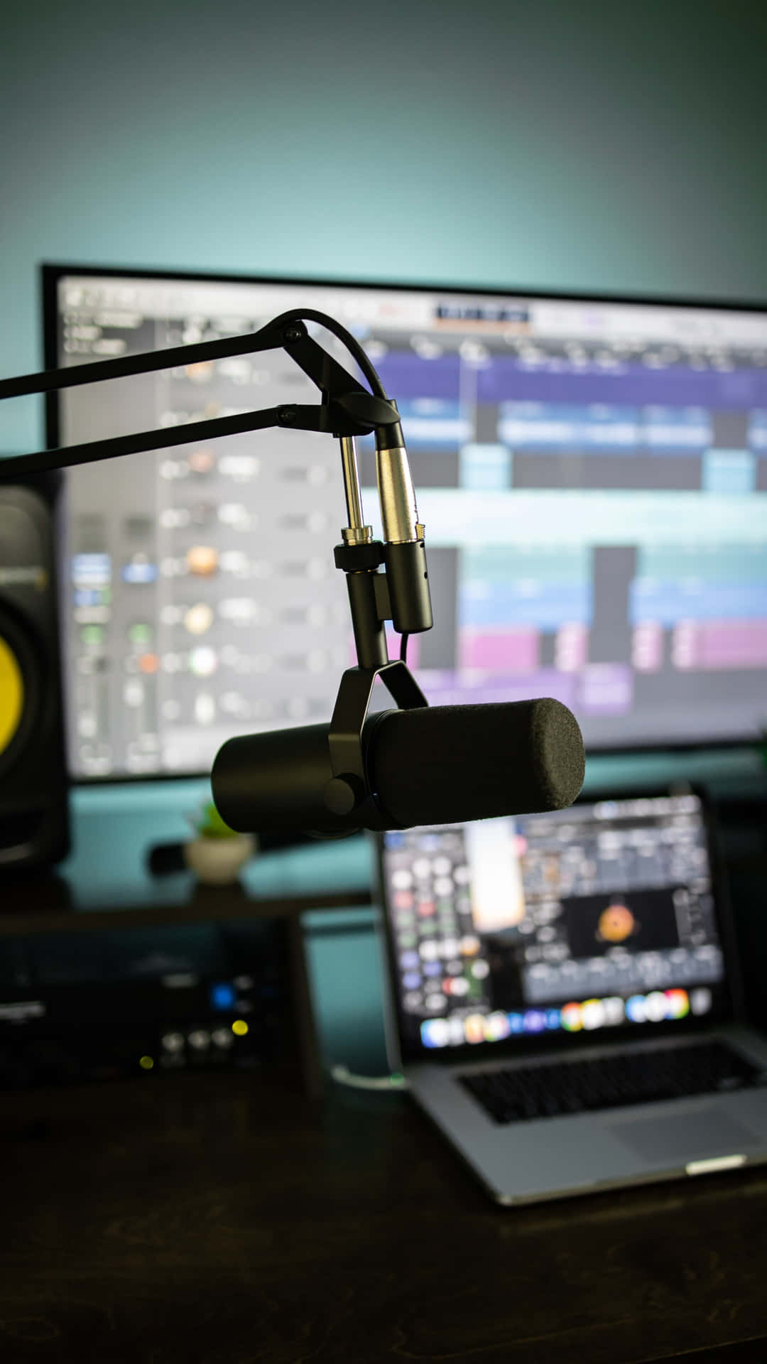 En mikrofon er på et skrivebord med en bærbar computer. Wallpaper