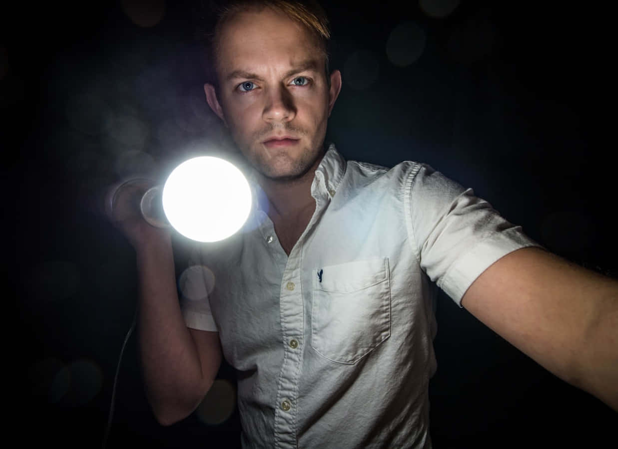 A Man Holding A Light Bulb In His Hand