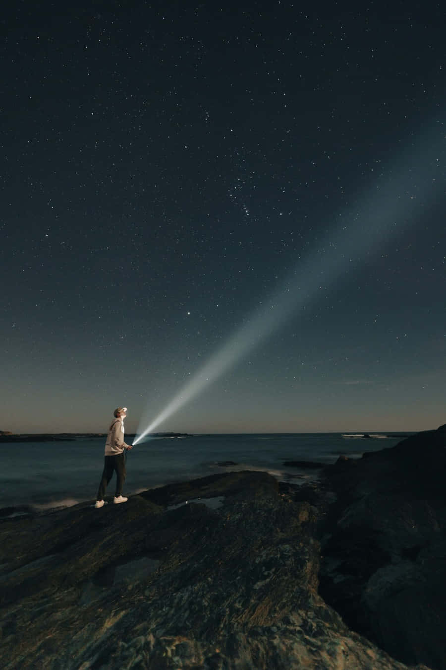 A Man Standing On A Rock With A Flashlight