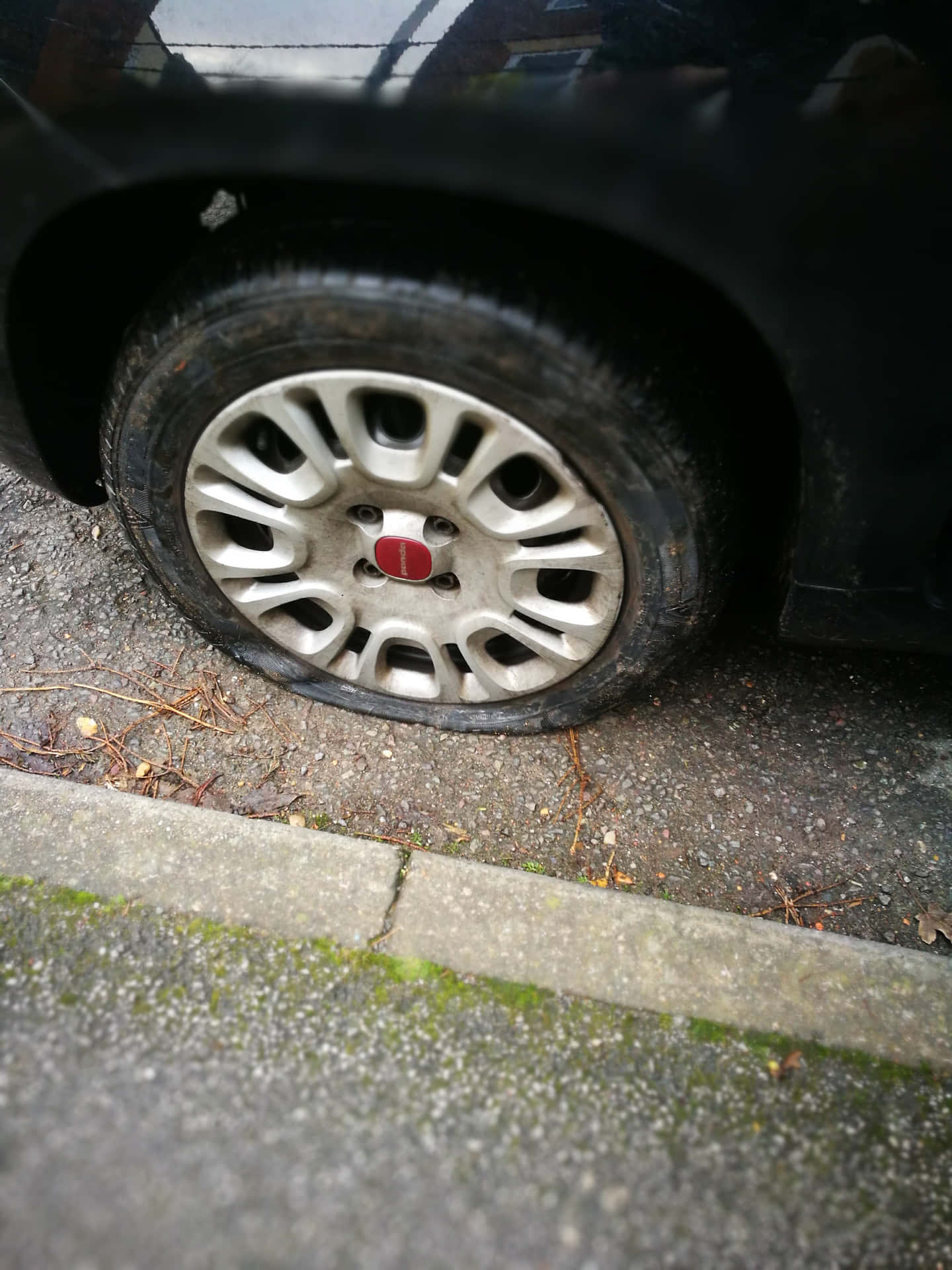 A car with a flat tire stranded on the roadside