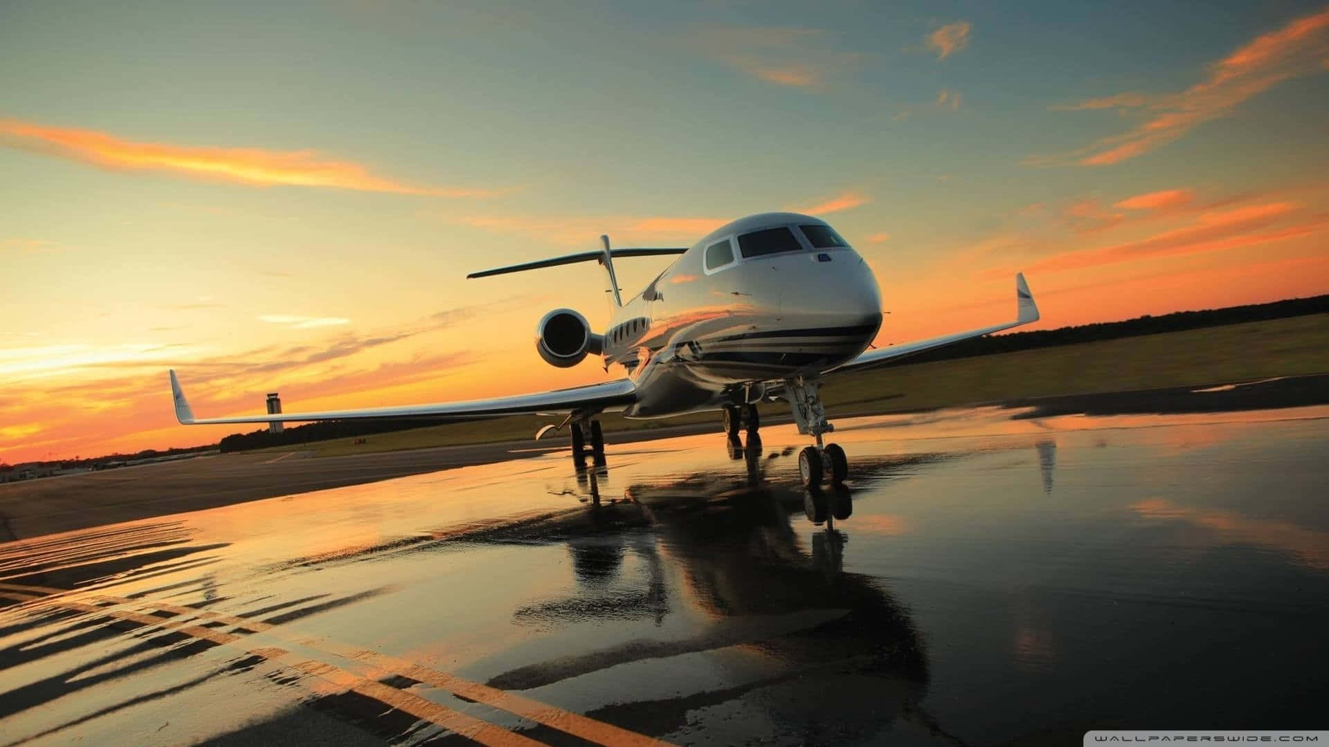 En privat jet, der sidder på rullebanen ved solnedgang. Wallpaper