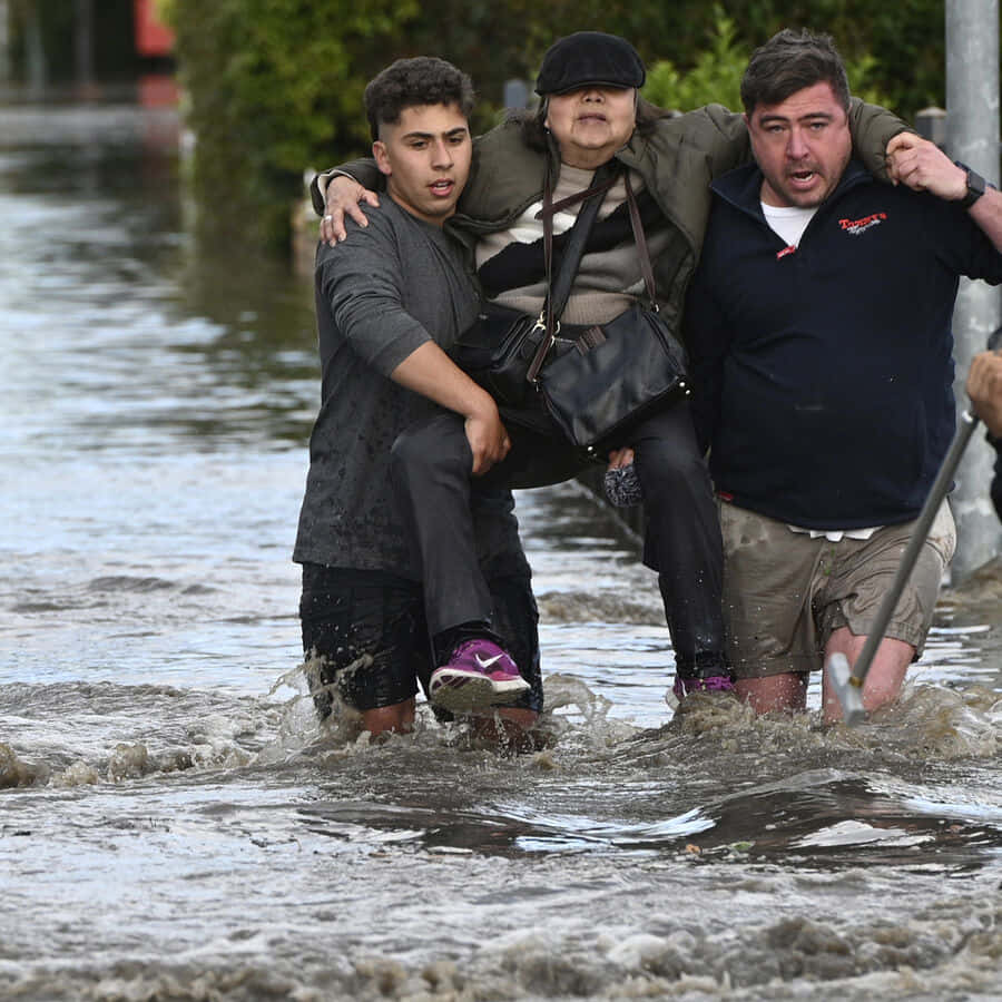 A Man And Woman Are Being Carried Through A Flooded Street