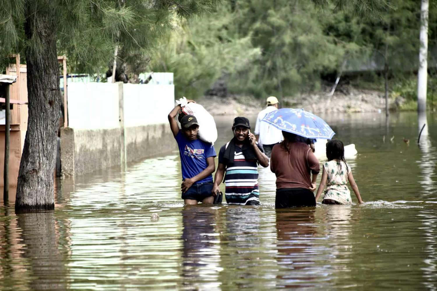 A Group Of People Walking Through A Flooded Street