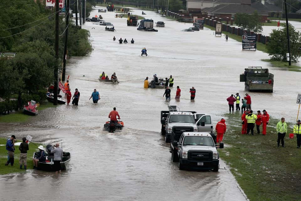 Menschengehen Eine Überflutete Straße Entlang, Begleitet Von Booten.
