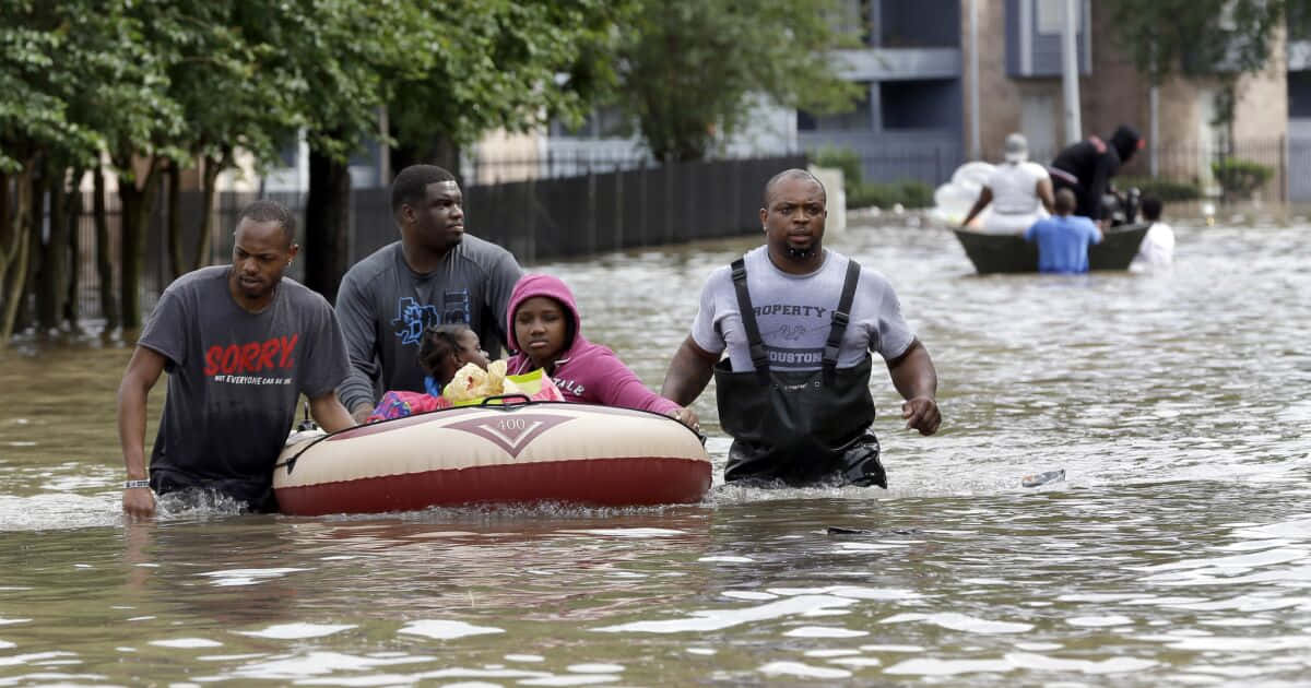A Group Of People Are Pushed Through A Flooded Street