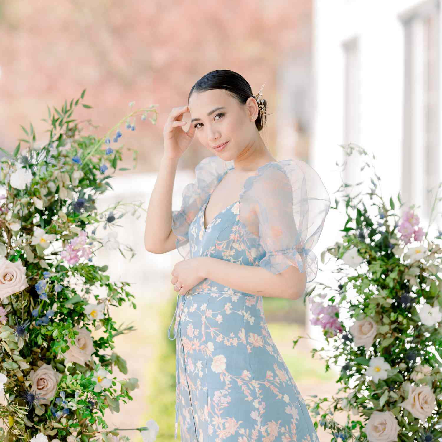 A Woman In A Blue Dress Posing In Front Of Flowers