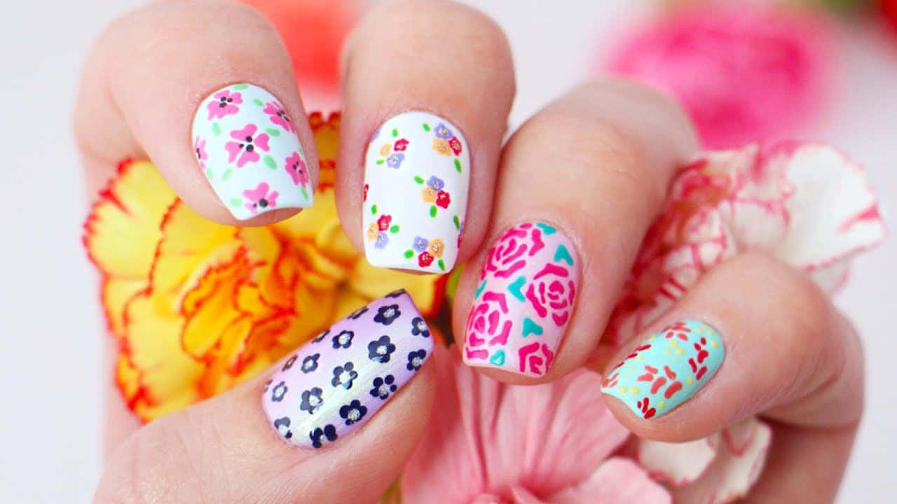 a woman is holding up a flower nail art design