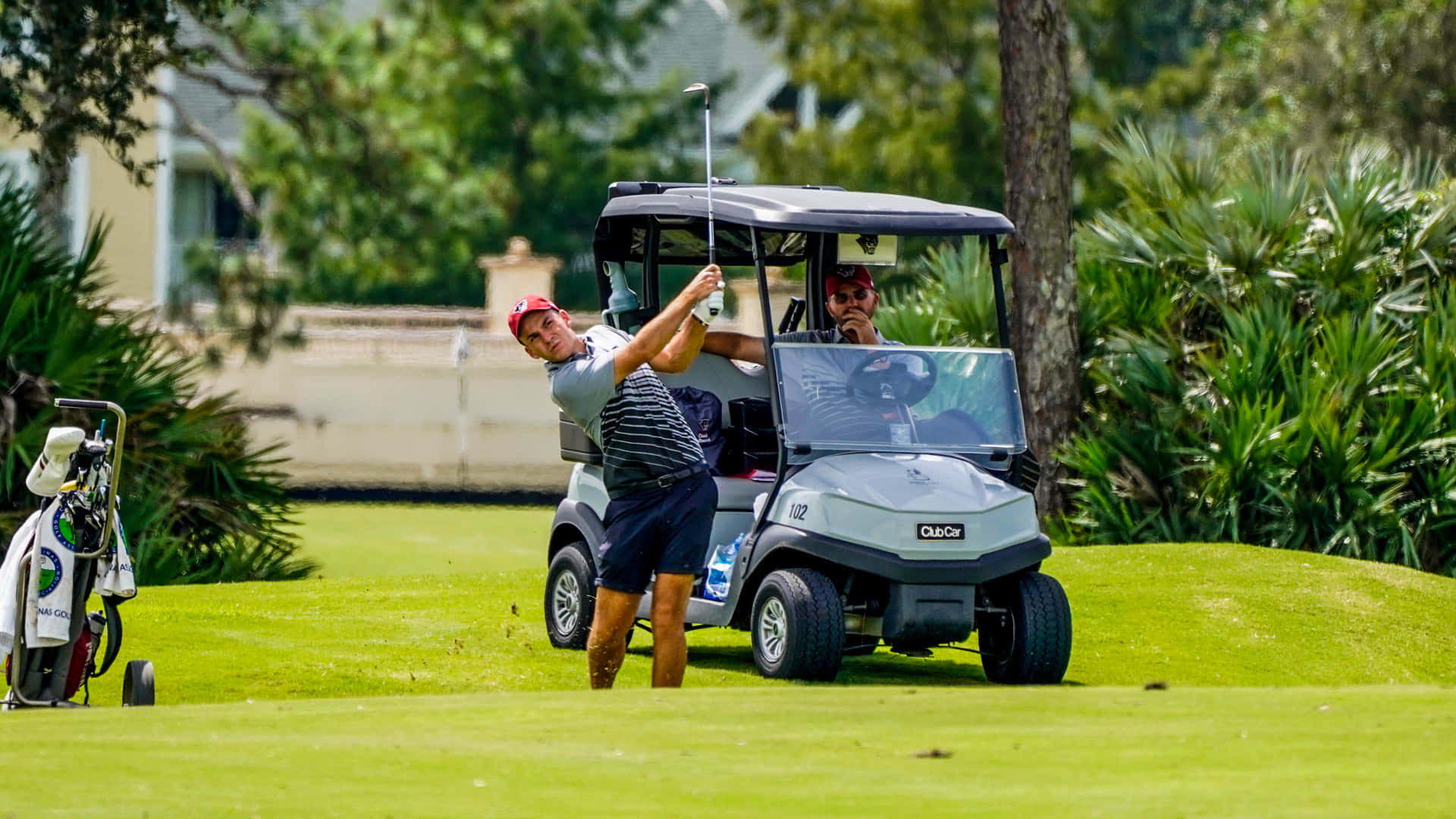 A Man Is Playing Golf With A Golf Cart Wallpaper