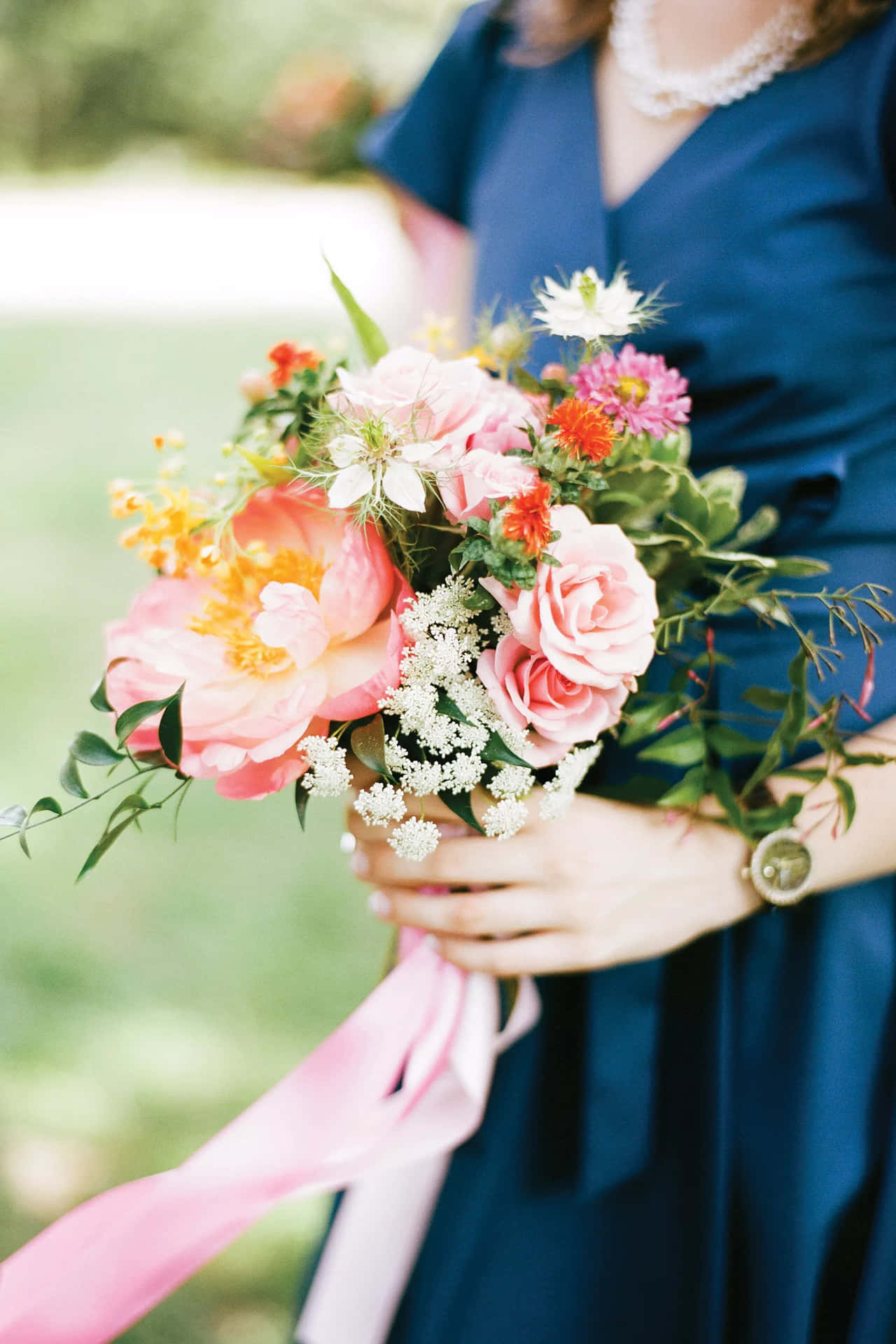 A Bridesmaid Holding A Bouquet Of Pink And Blue Flowers