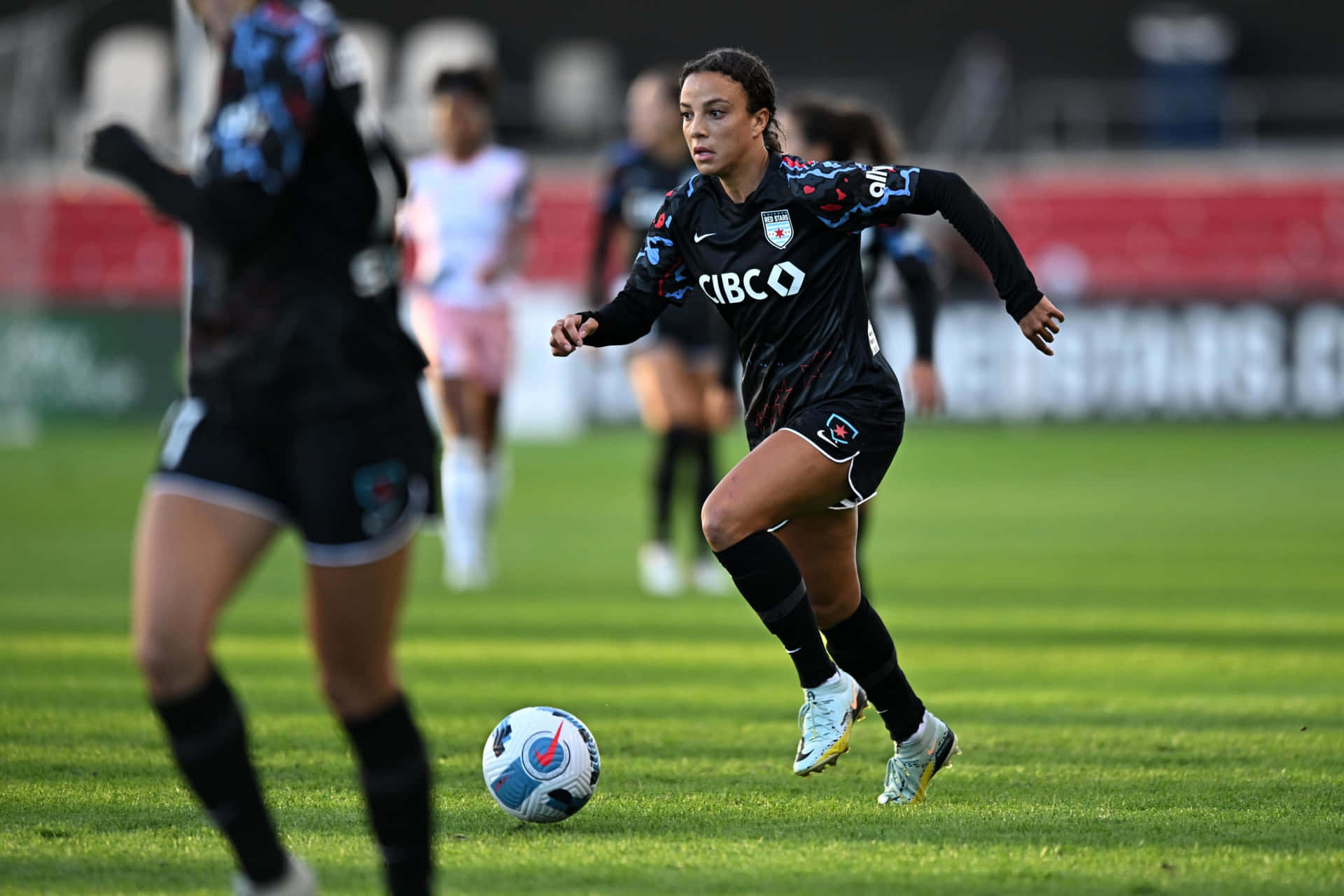 Joueuse De Football Concentrée Dribblant Le Ballon Fond d'écran