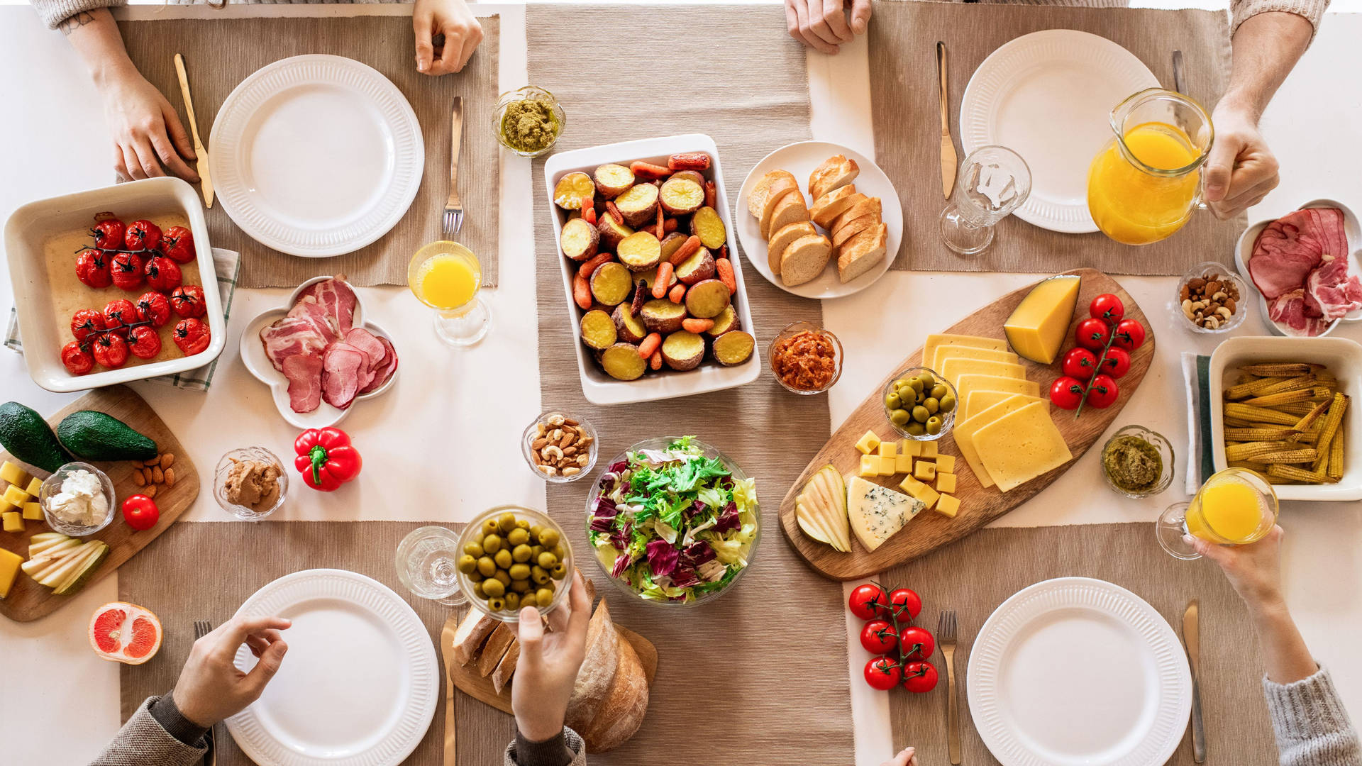 En gruppe mennesker sidder rundt om et bord med mad på bordet. Wallpaper