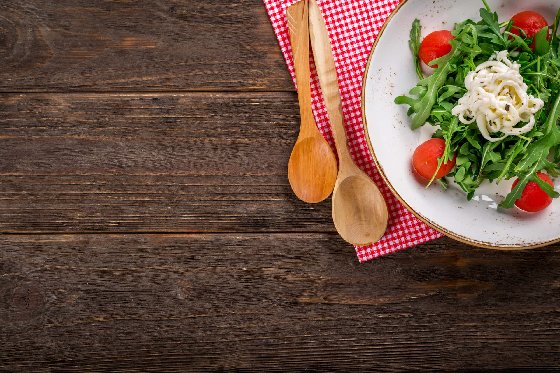 A Plate Of Salad With Tomatoes And A Wooden Spoon Wallpaper