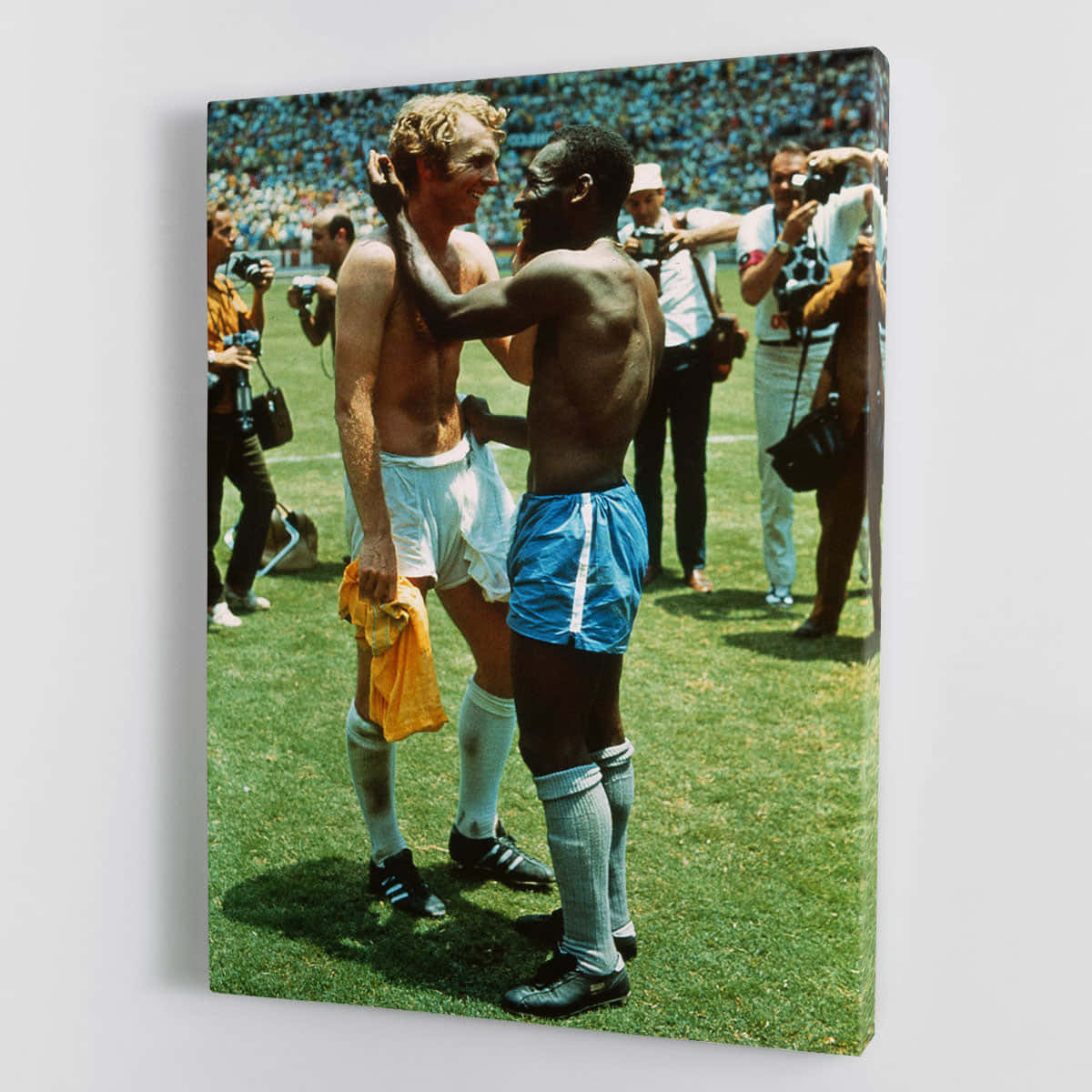 Fodboldatleter Bobby Moore og Pelé strækker sig i en pose på en grøn fodboldbane sammen. Wallpaper