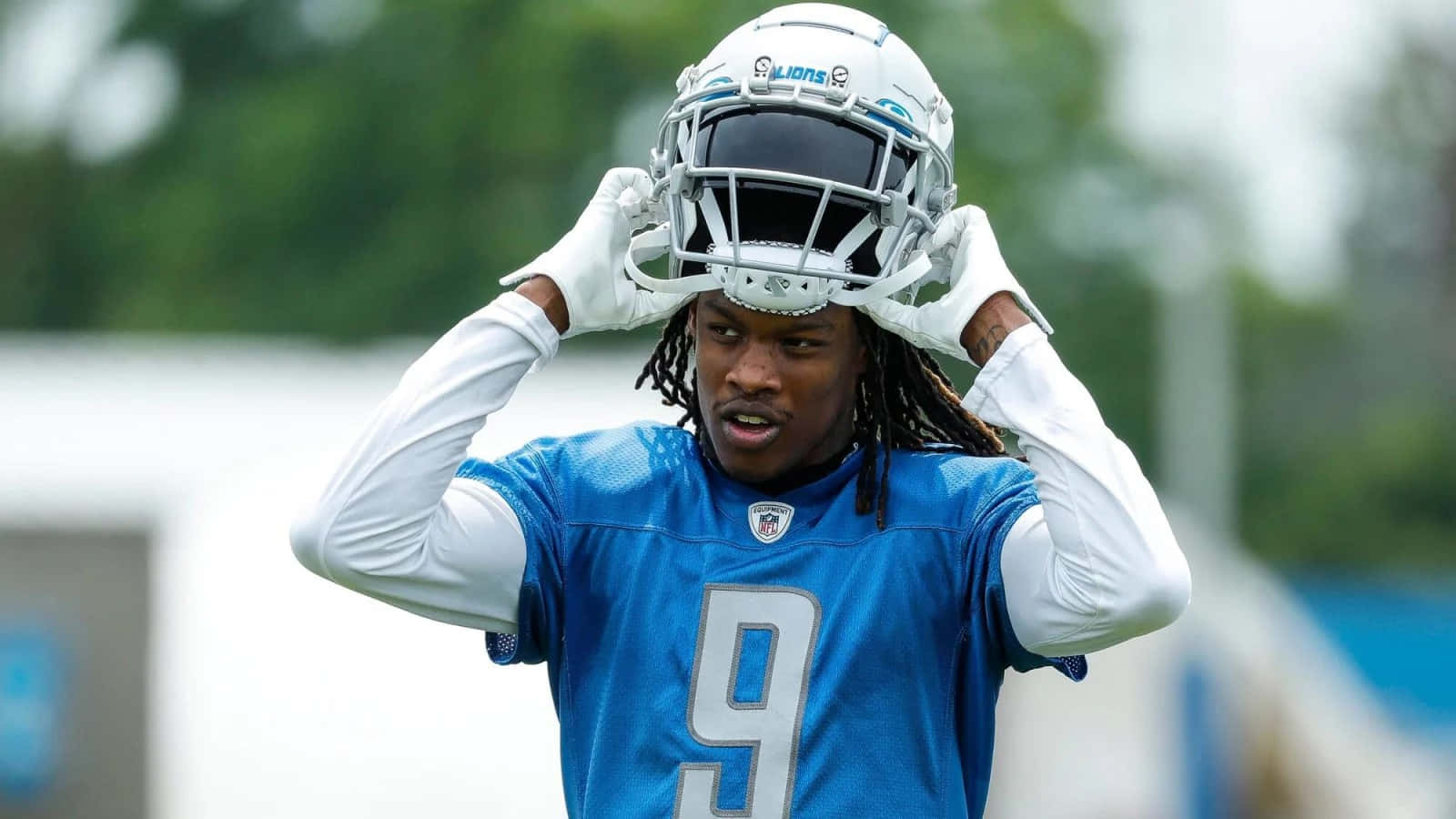 Football Player Adjusting Helmet During Practice Wallpaper