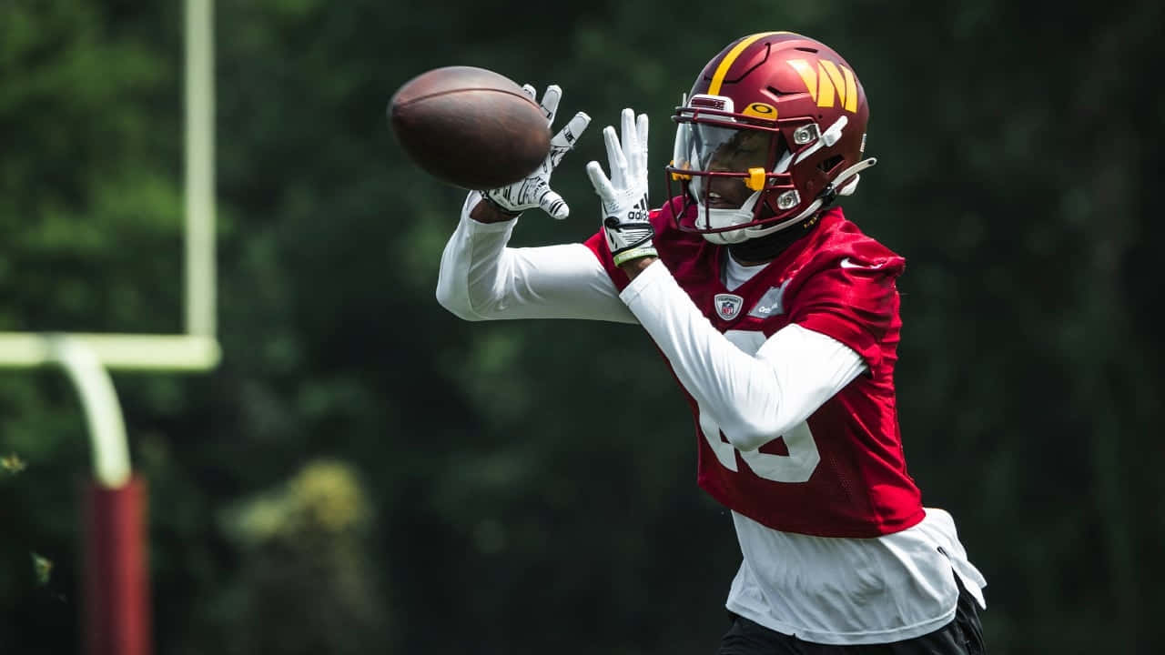 Football Player Catching Ball During Practice Wallpaper